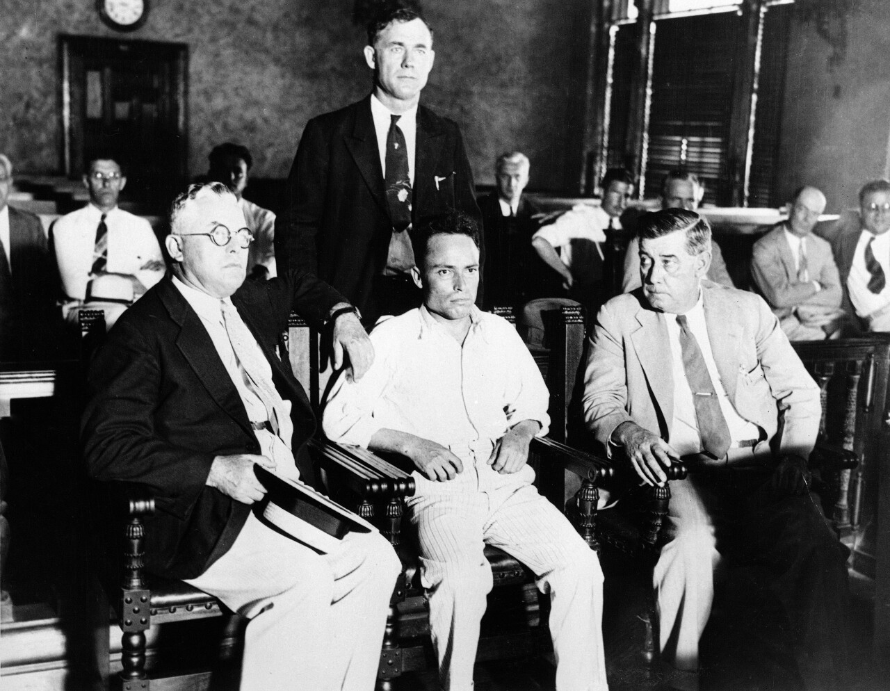 Giuseppe Zangara, Hackensack, N.J. bricklayer, center, is shown in criminal court in Miami, Fla., Feb. 17, 1933, surrounded by unidentified deputies, waiting for arraignment for his attempt to assassinate President-elect Franklin Roosevelt and wounding Chicago Mayor Anton Cermak, and four others, on Feb. 15. Arraignment was postponed. (AP Photo)