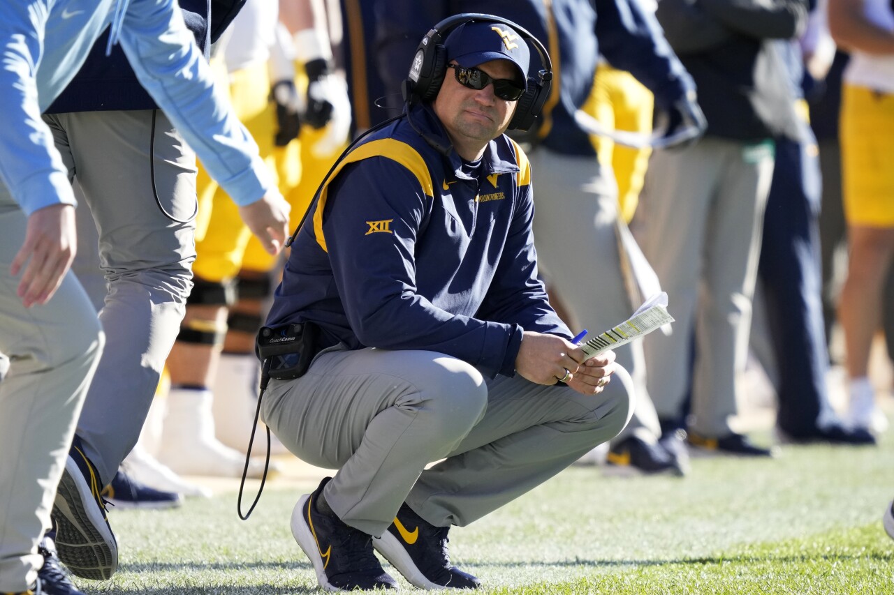 West Virginia Mountaineers head coach Neal Brown crouches on sideline in 2022