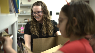 Delilah Brahm and her sister Lorelai (front) organize books at Gulf Coast JFCS. 