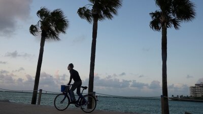 A cyclist rides as the sun rises, Wednesday, Oct. 30, 2024, in Miami Beach, Fla.  (AP Photo/Marta Lavandier)