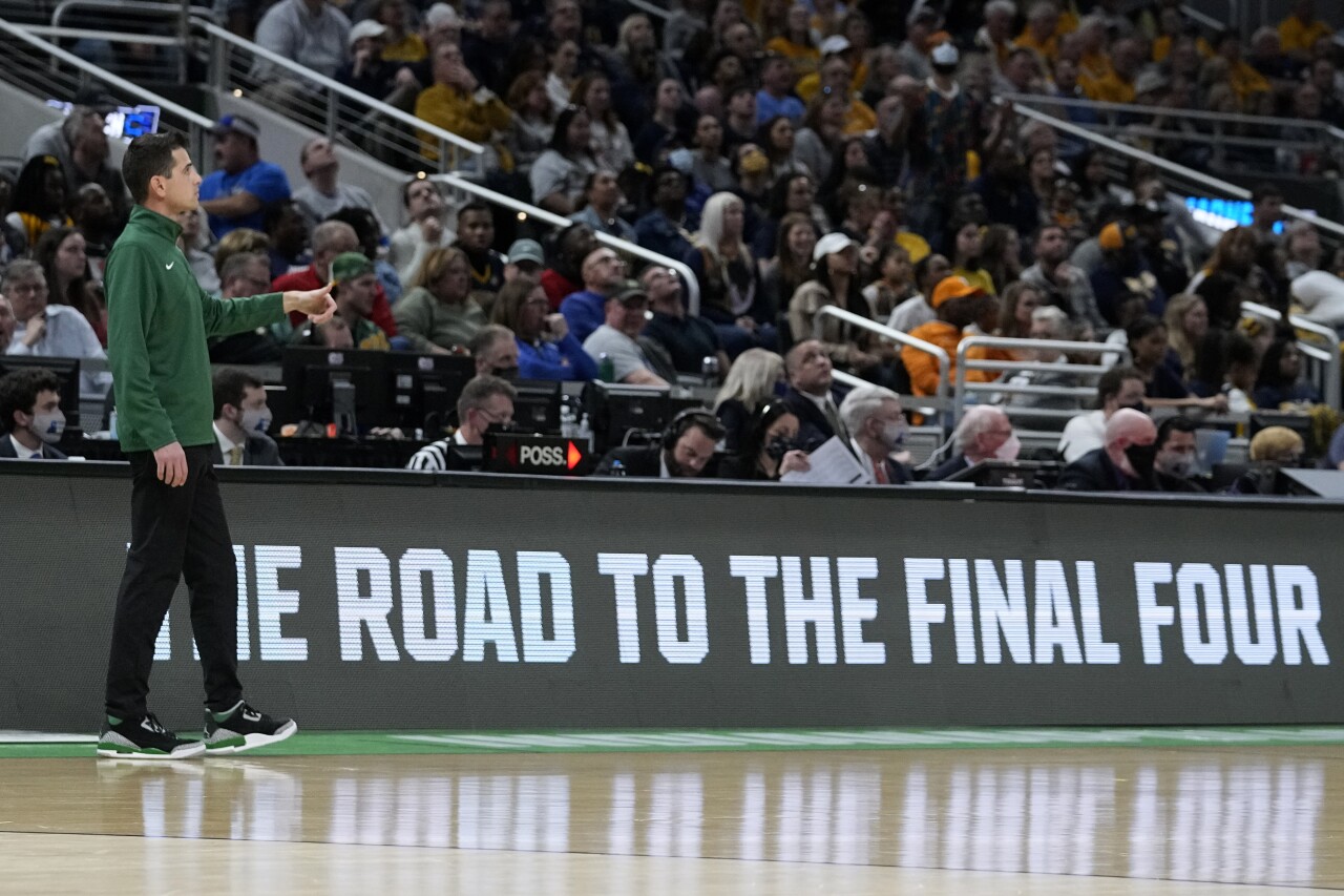 Todd Golden stands in front of 'The Road to the Final Four' sign