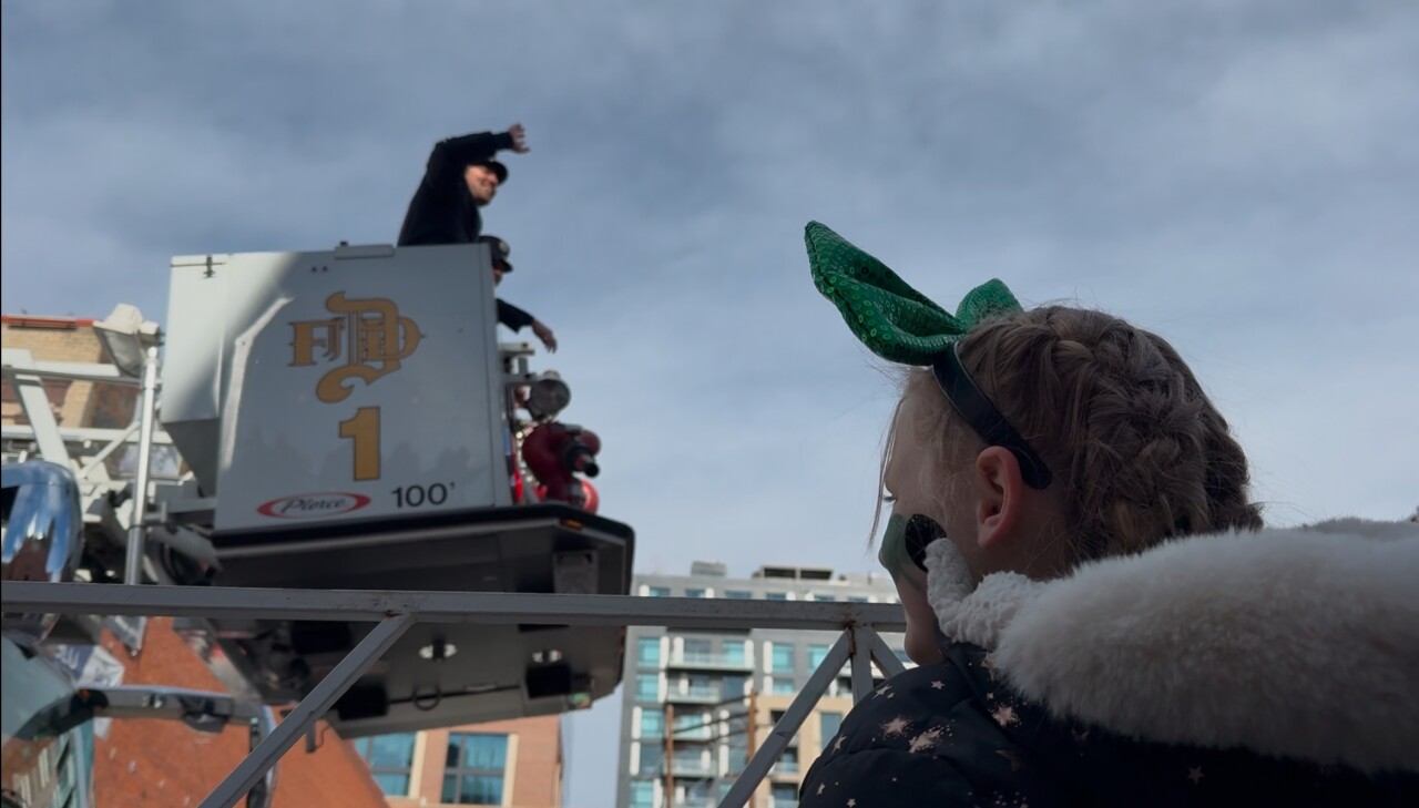 A girl waves at a Denver St. Patrick's Day Parade float.