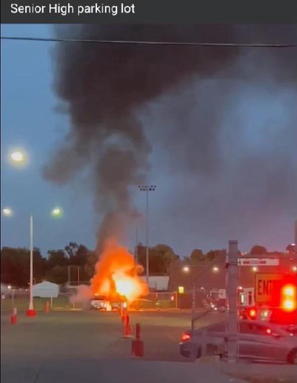 Two vehicles engulfed in flames in front of Senior High School