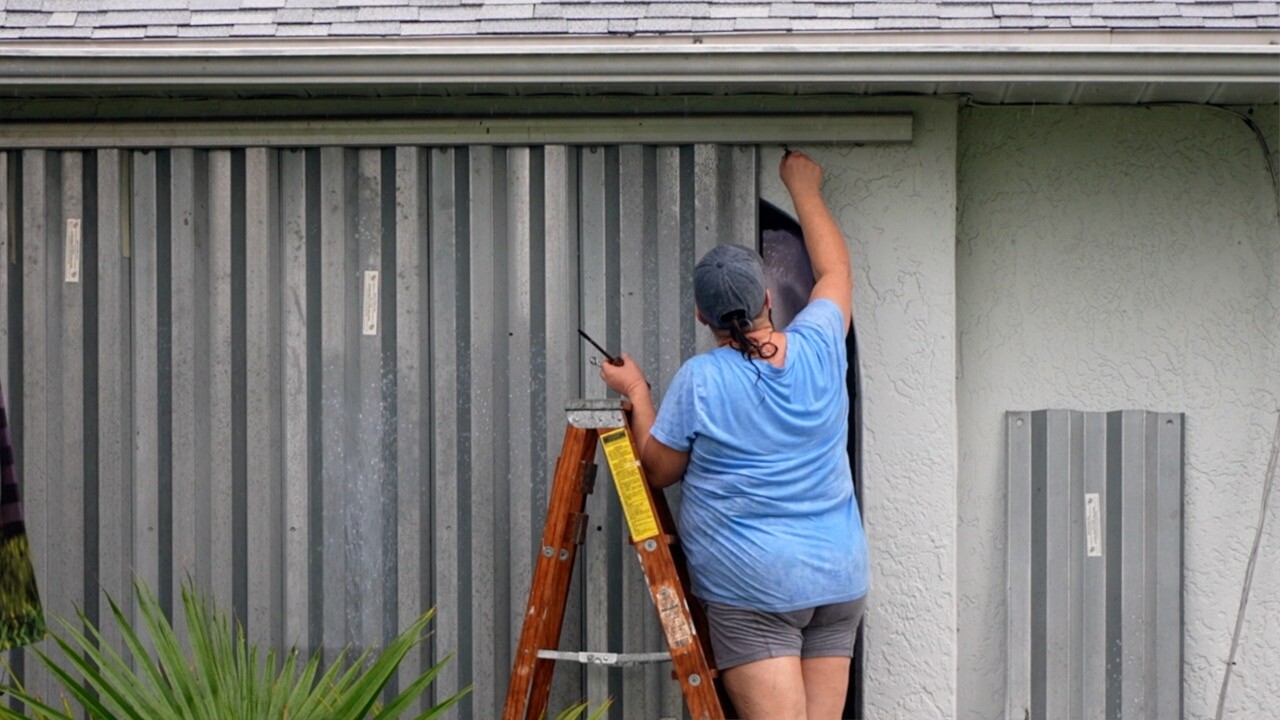 Cape Coral resident putting up storm shutters on their home.