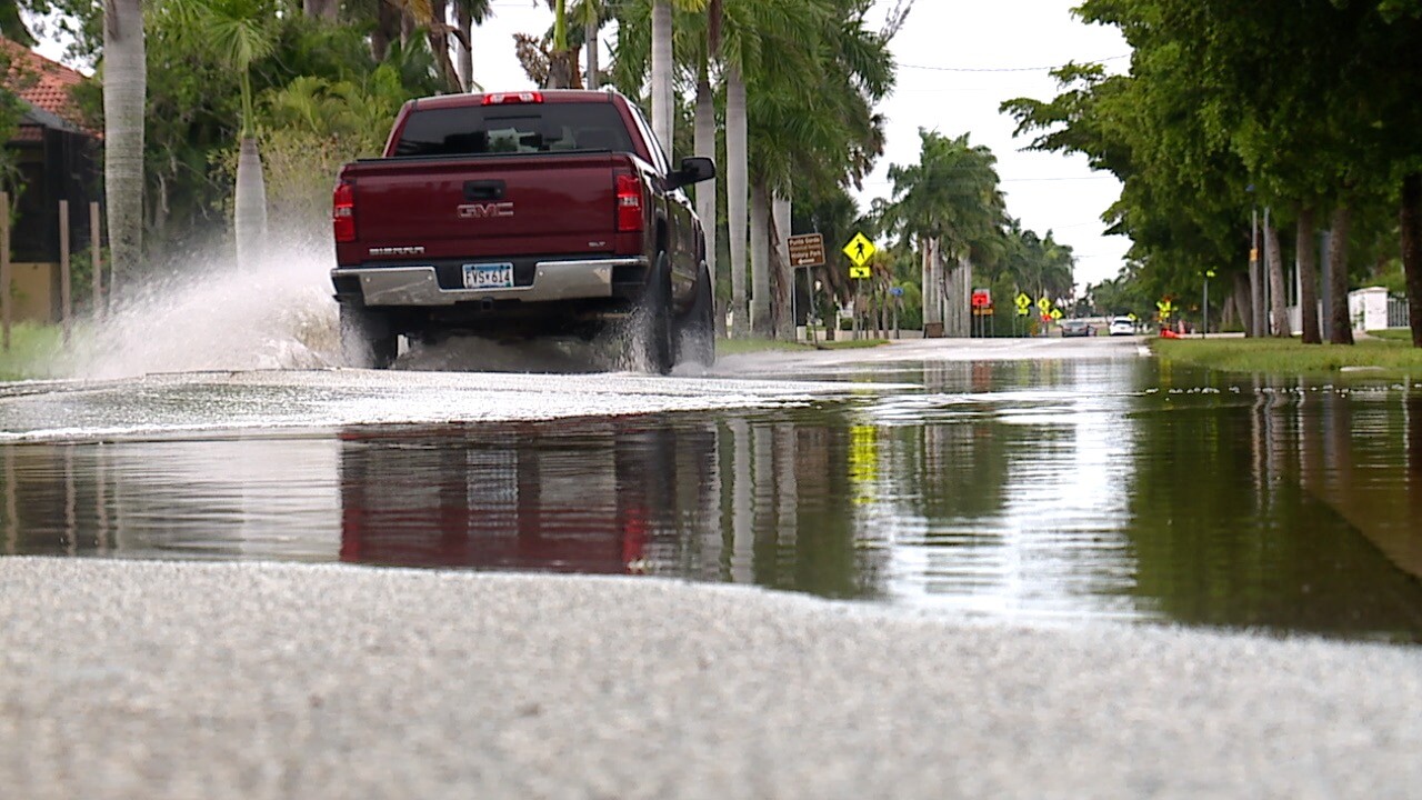 Truck making waves as it drives through inches of standing water on West Marion Avenue.