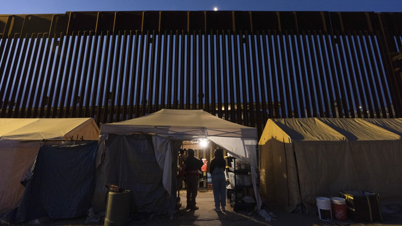 Volunteers talk in a tent along a border wall separating Mexico from the United States.
