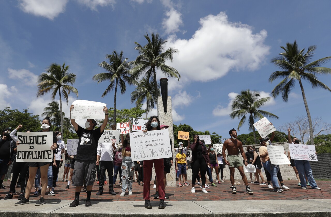 Protesters hold signs at Torch of Freedom in downtown Miami, May 30