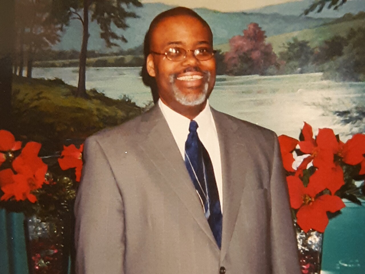 Herndon Anderson smiles in an undated photo. He is wearing glasses and is dressed in a white shirt, a blue patterned tie and a grey suit.