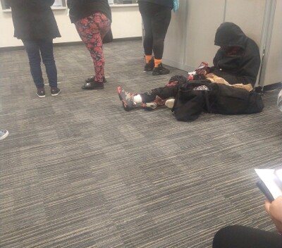 A person sits on the  floor in a crowded SNAP benefits office