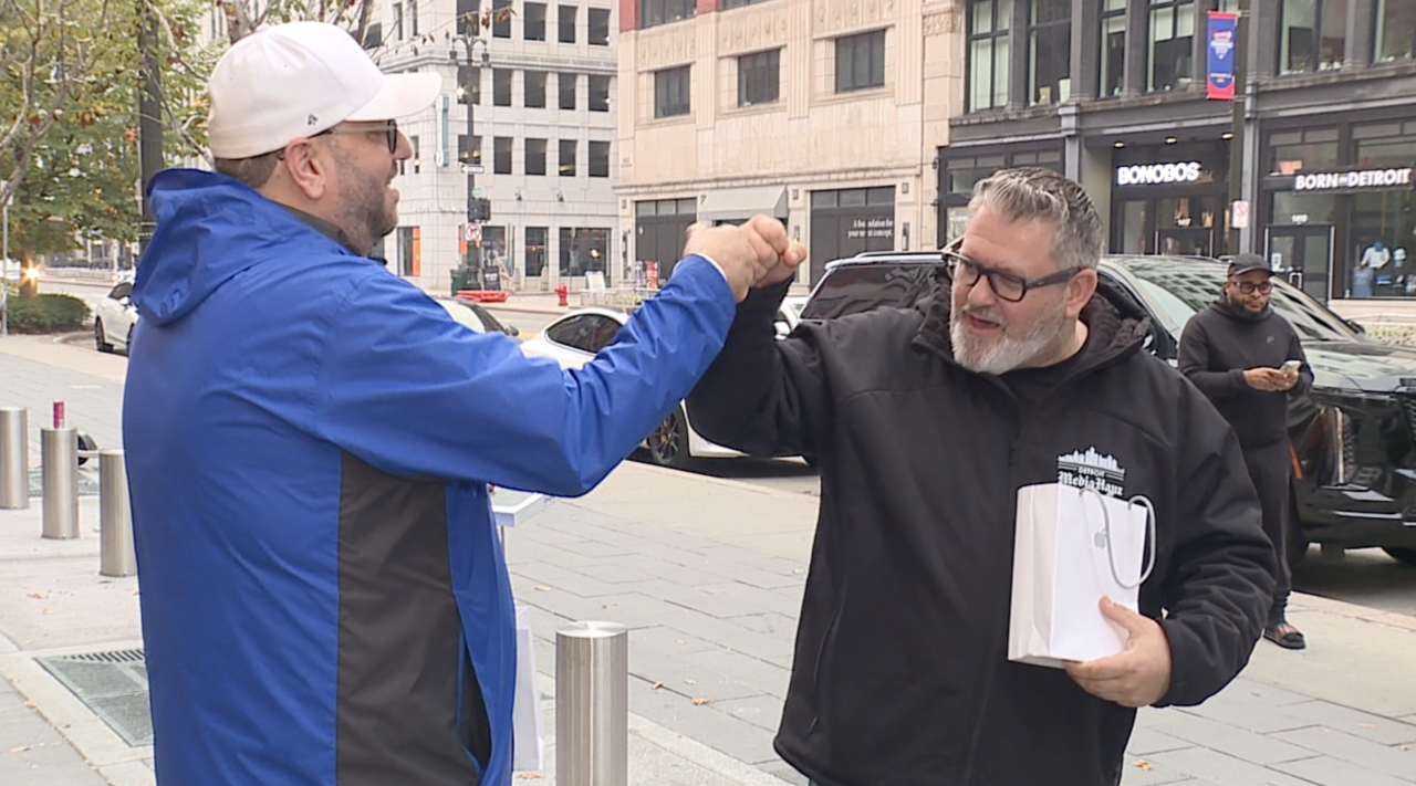 Friends share fist bump after purchasing iPhone Duo at Apple's downtown Detroit store