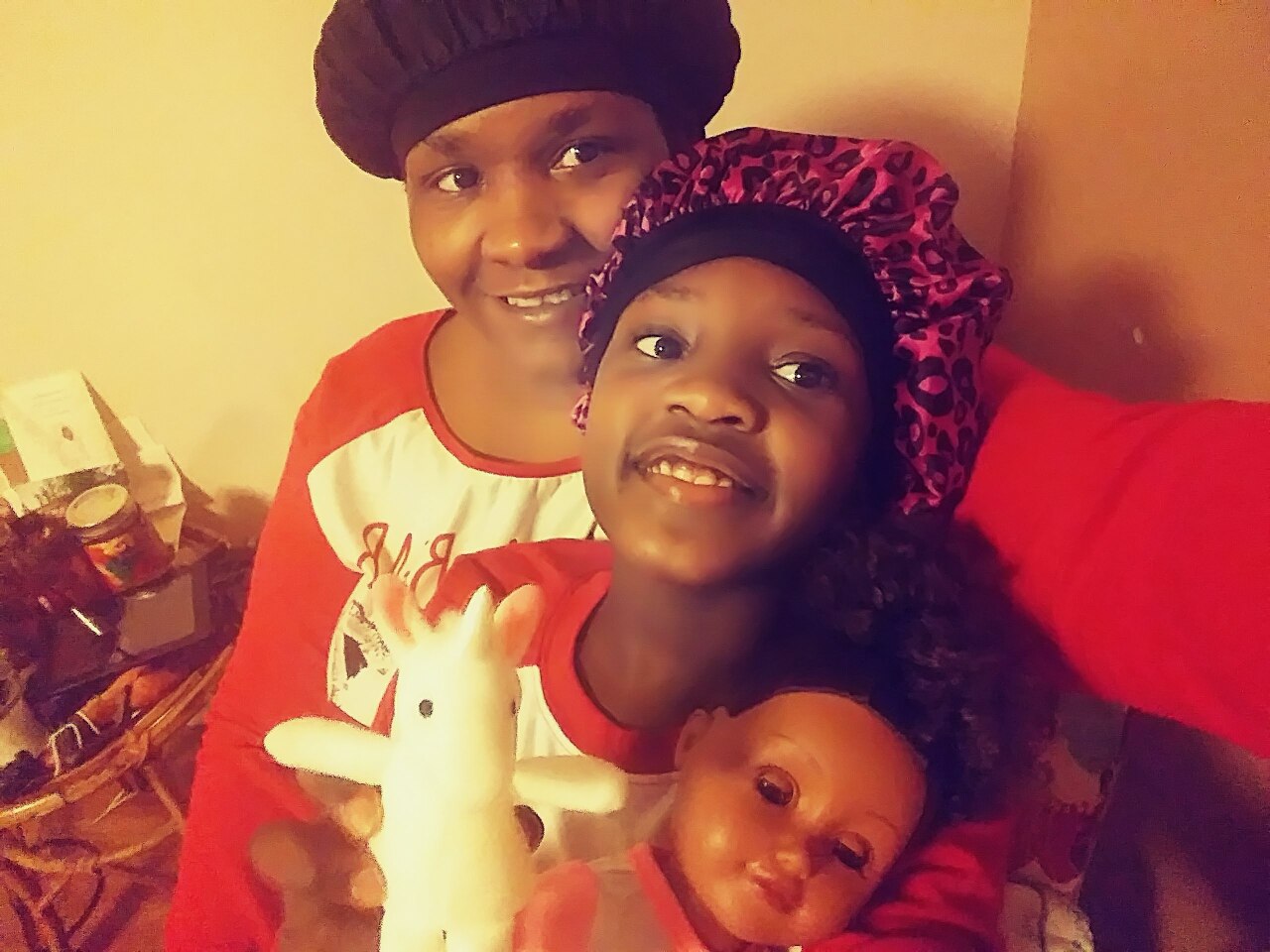 Kendra Davis smiles as she takes a photo with her daughter, who also is smiling and holding a baby doll and unicorn toy.