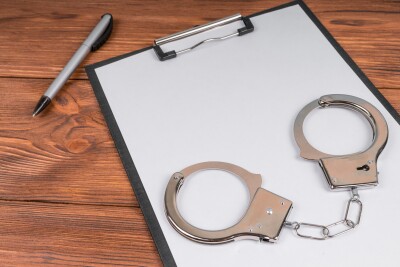 Handcuffs,On,A,Tablet,With,A,Blank,Sheet,Of,Paper.