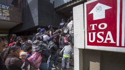 Members of a caravan of Central Americans who spent weeks traveling across Mexico walk from Mexico to the U.S. side of the bo