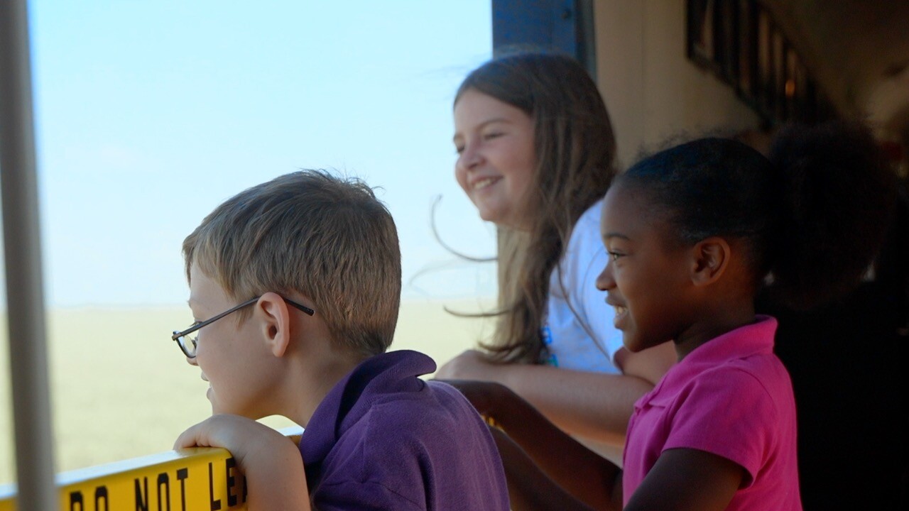 Three students taking in the bucolic views from the open-air car of the Sugar Express.