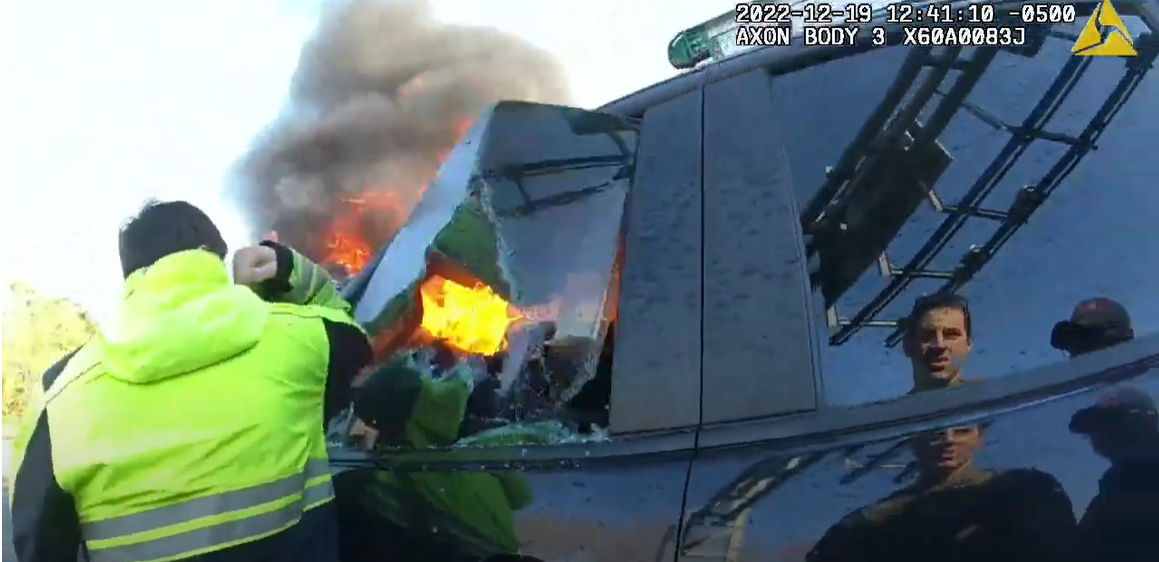 A Prince George's County Fire Department crew member uses his elbow to break open the window of a burning vehicle