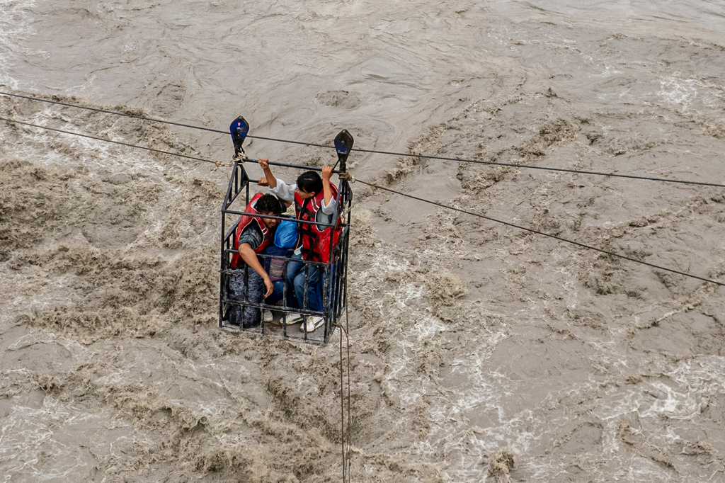 Residents commute across the Trishuli River on a newly installed zipline in the aftermath of flash floods at Bidur in Nepal's Nuwakot district, Thursday, Sept. 3, 2026.