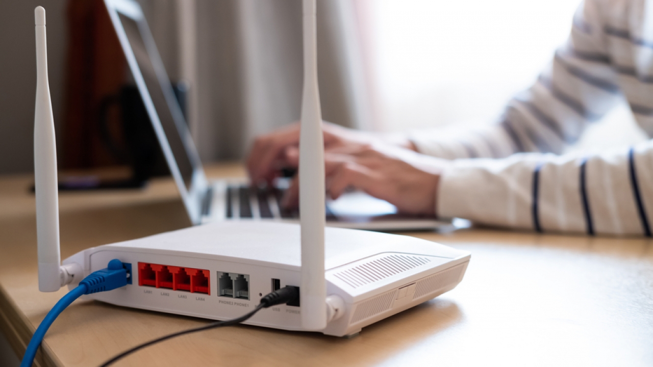 Person types on a laptop near an internet router.