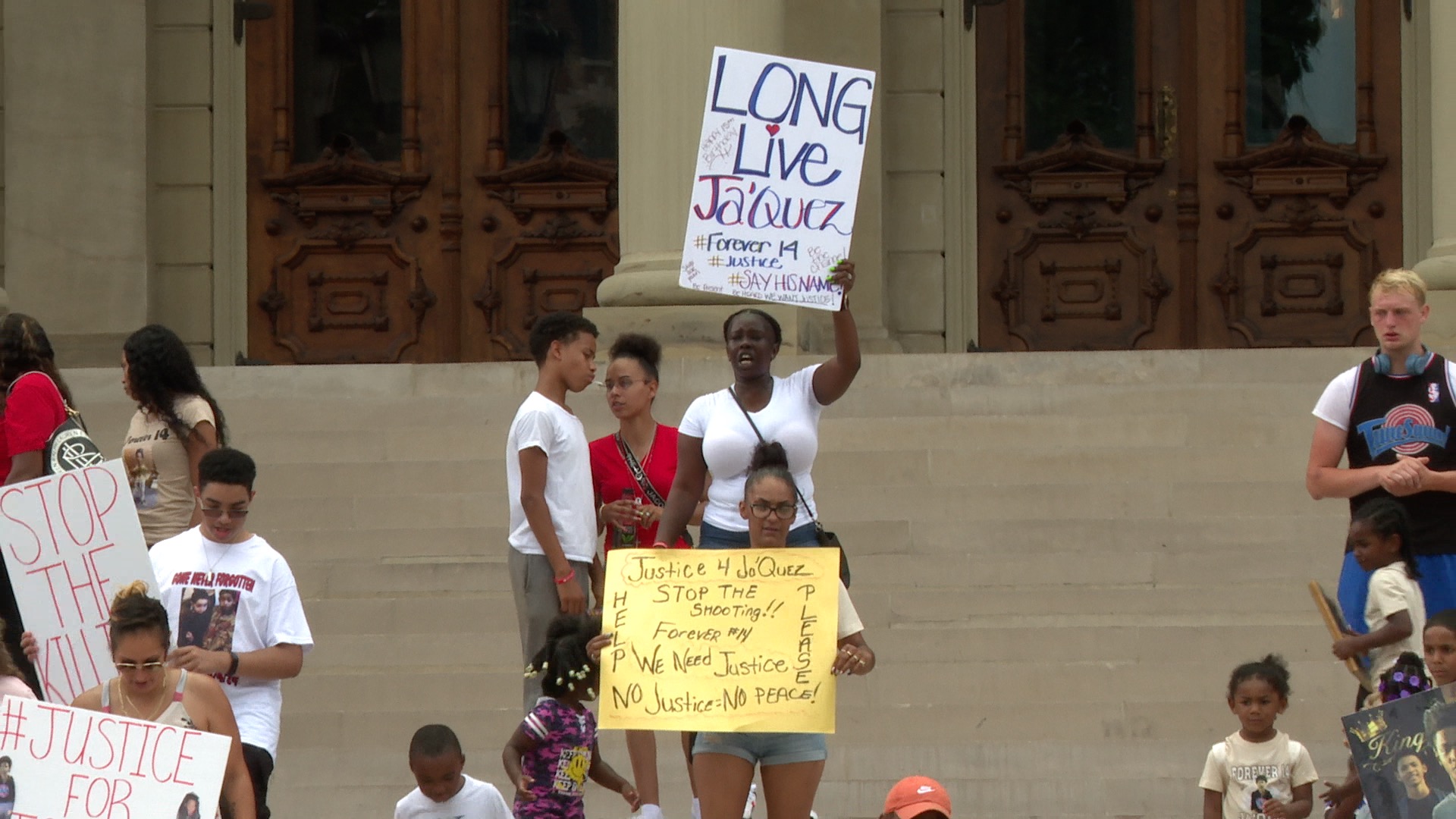 Aunt of Ja'Quez Moye-Young holds sign at a rally in his honor