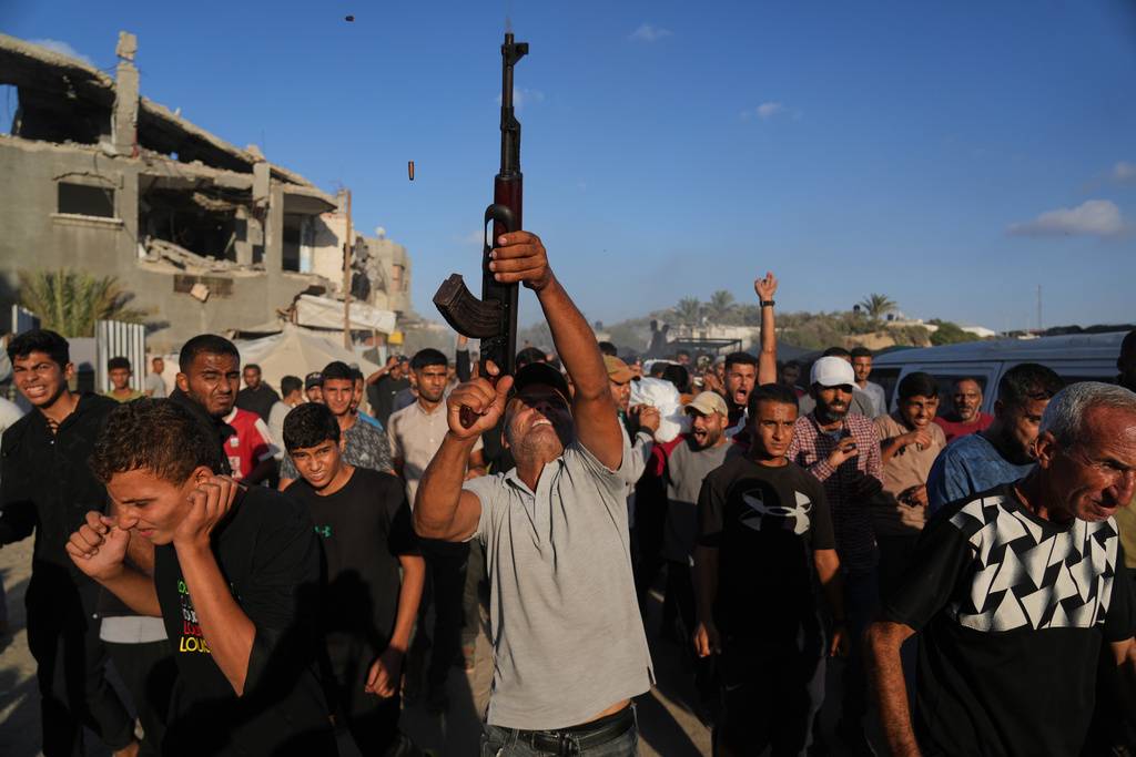 An armed man shoots in the air during the funeral of Palestinians killed by Israeli fire, in Deir al-Balah, Gaza Strip.