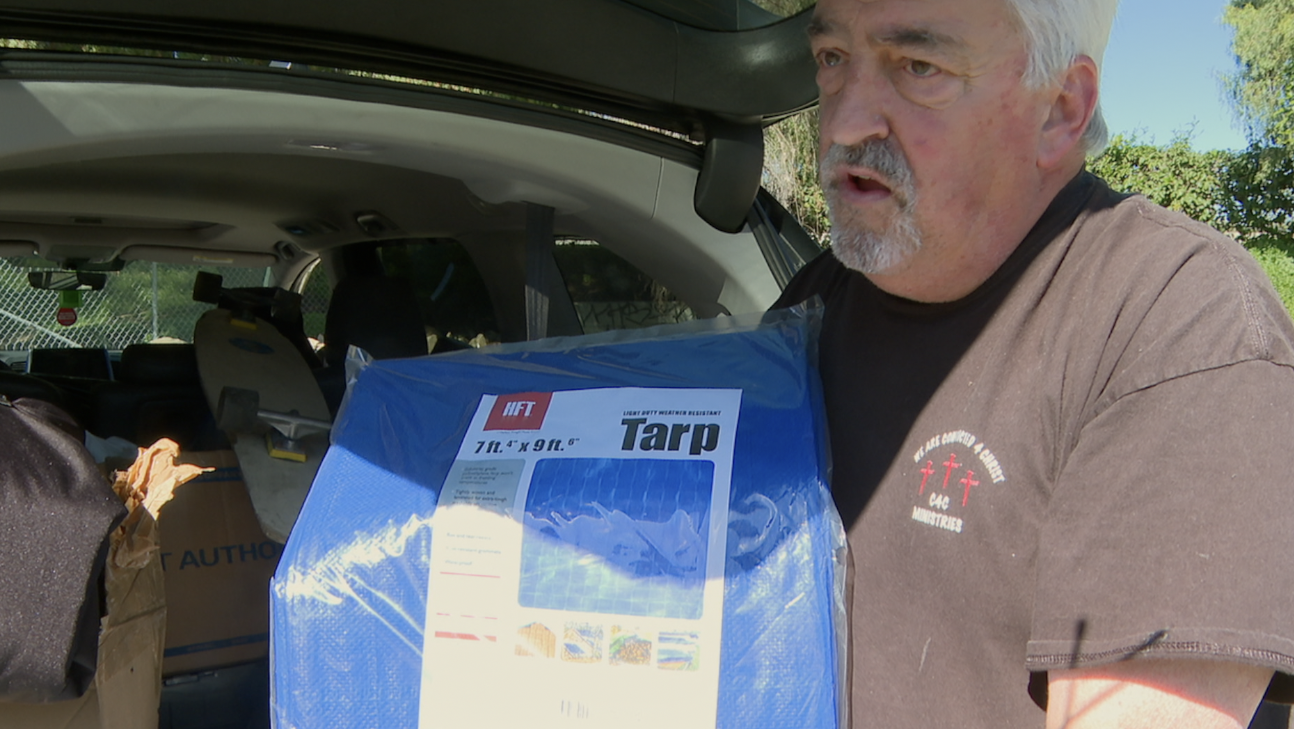 Michael Aplikowsky holds up some tarps he's been giving out to the homeless.