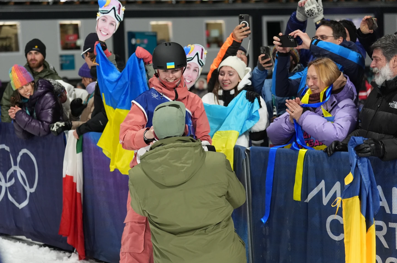 Ukraine's Kateryna Kotsar gets a proposal from Bohdan Fashtryha, front, as she competes in the women's freestyle skiing big air qualifications at the 2026 Winter Olympics, in Livigno, Italy, Saturday, Feb. 14, 2026. 