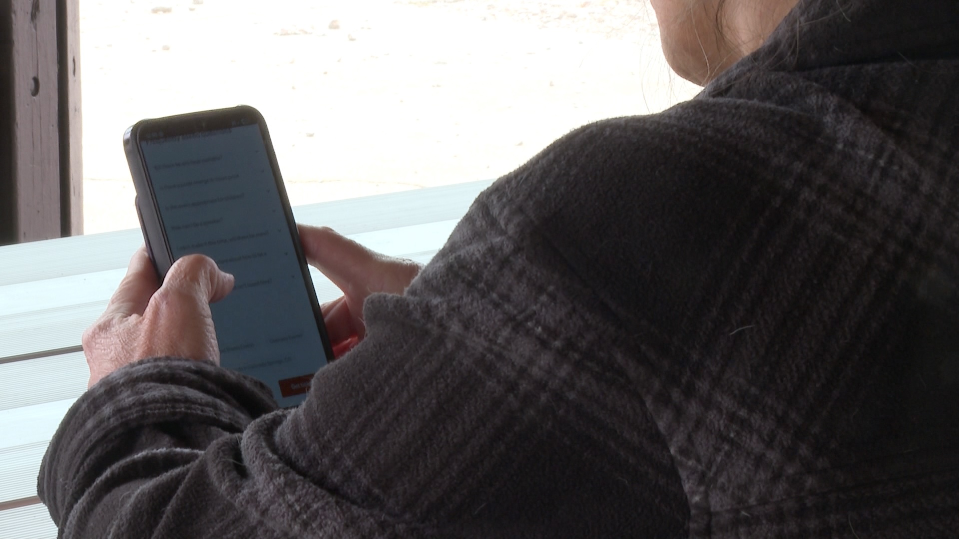 Woman looks at phone screen while seated at table