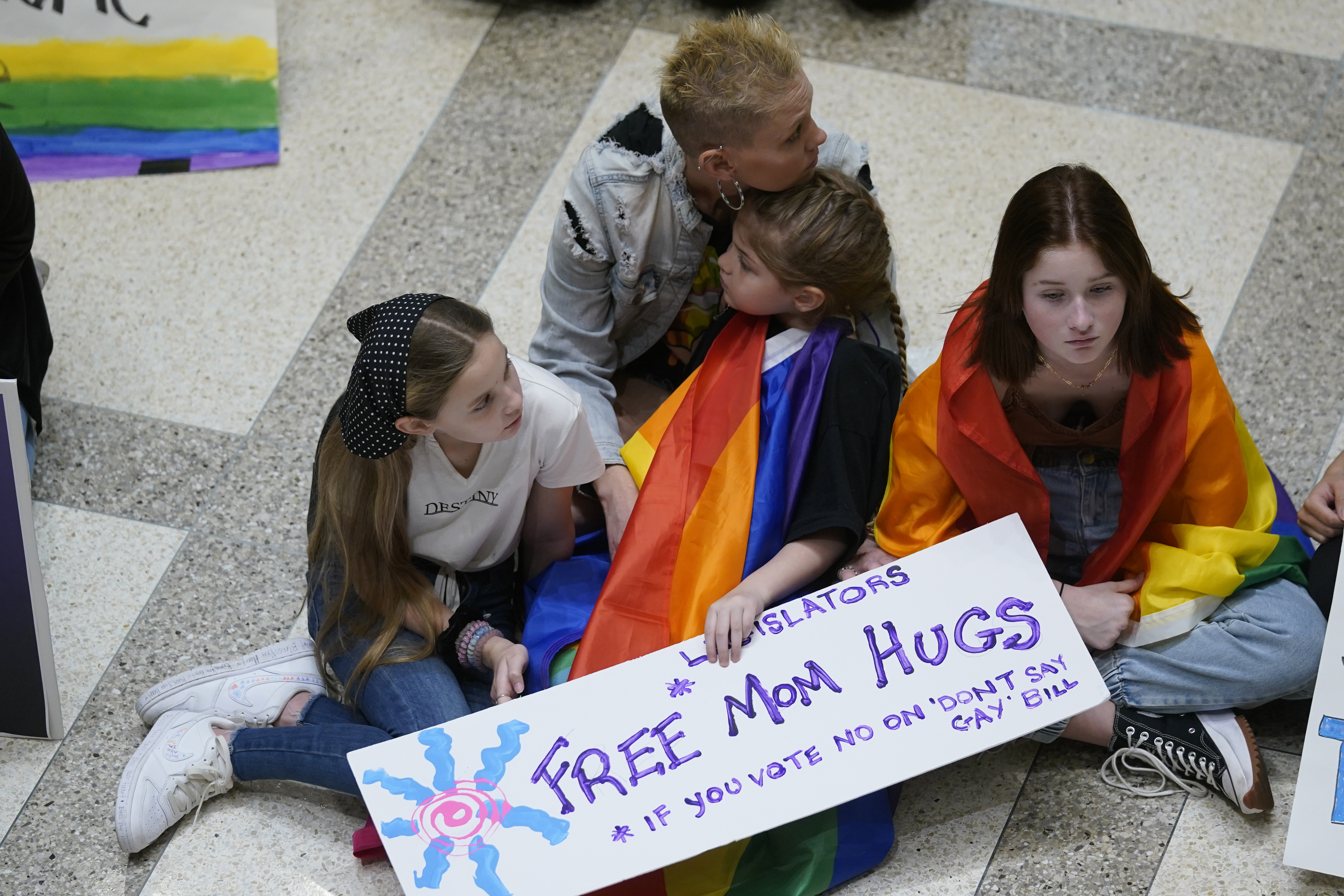 Families protest in Florida Capitol with sign "Free Mom Hugs If You Vote No On 'Don't Say Gay' Bill"