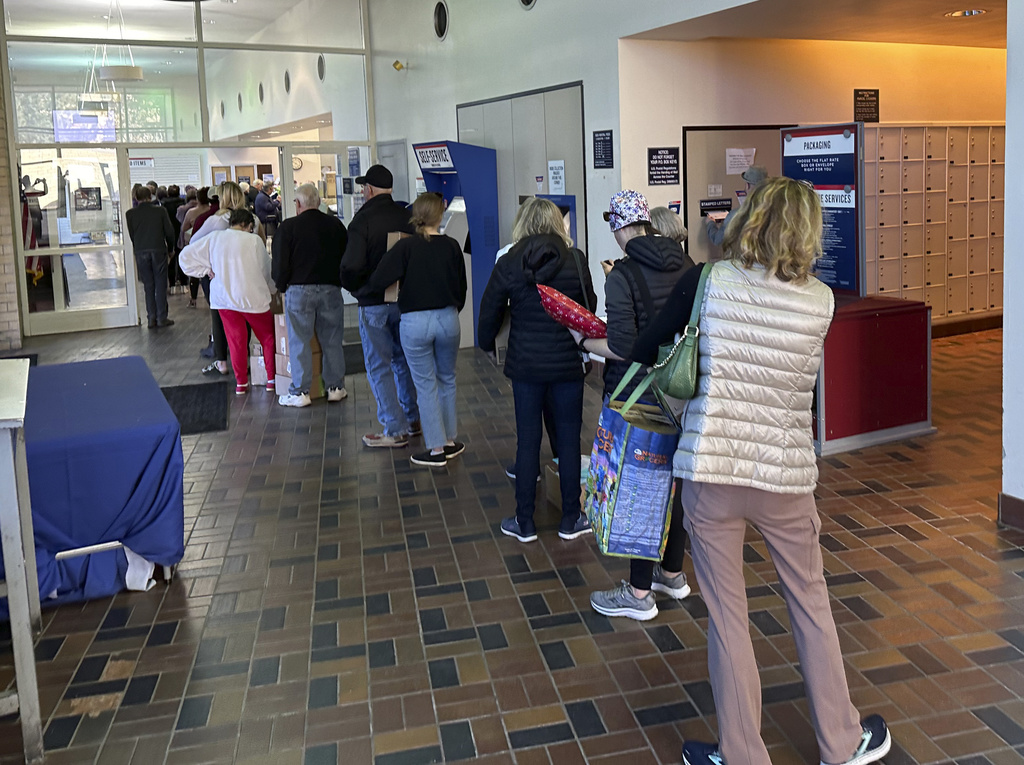 Customers queue up to drop off packages at the University Hills branch of the U.S. Postal Service on Saturday, Dec. 16, 2023, in southeast Denver. 