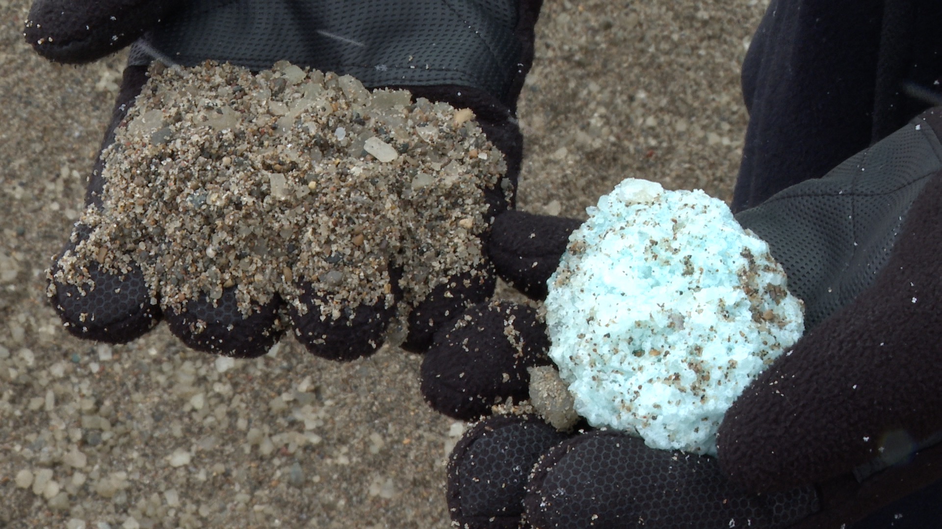 One hand with sand and another with a clump of rock salt