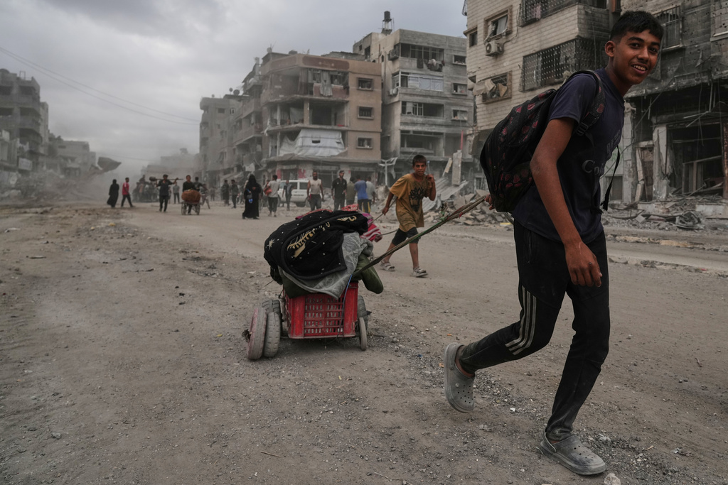 Displaced Palestinians walk with their belongings along the heavily damaged Al-Jalaa Street in Gaza City.