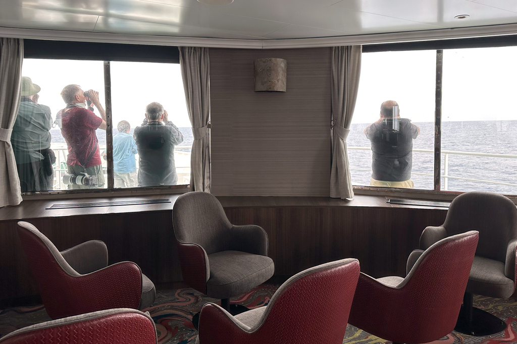 Passengers on the hantavirus-stricken cruise ship, MV Hondius, scan the horizon with binoculars during their voyage to Spain's port of Tenerife, May 6, 2026.