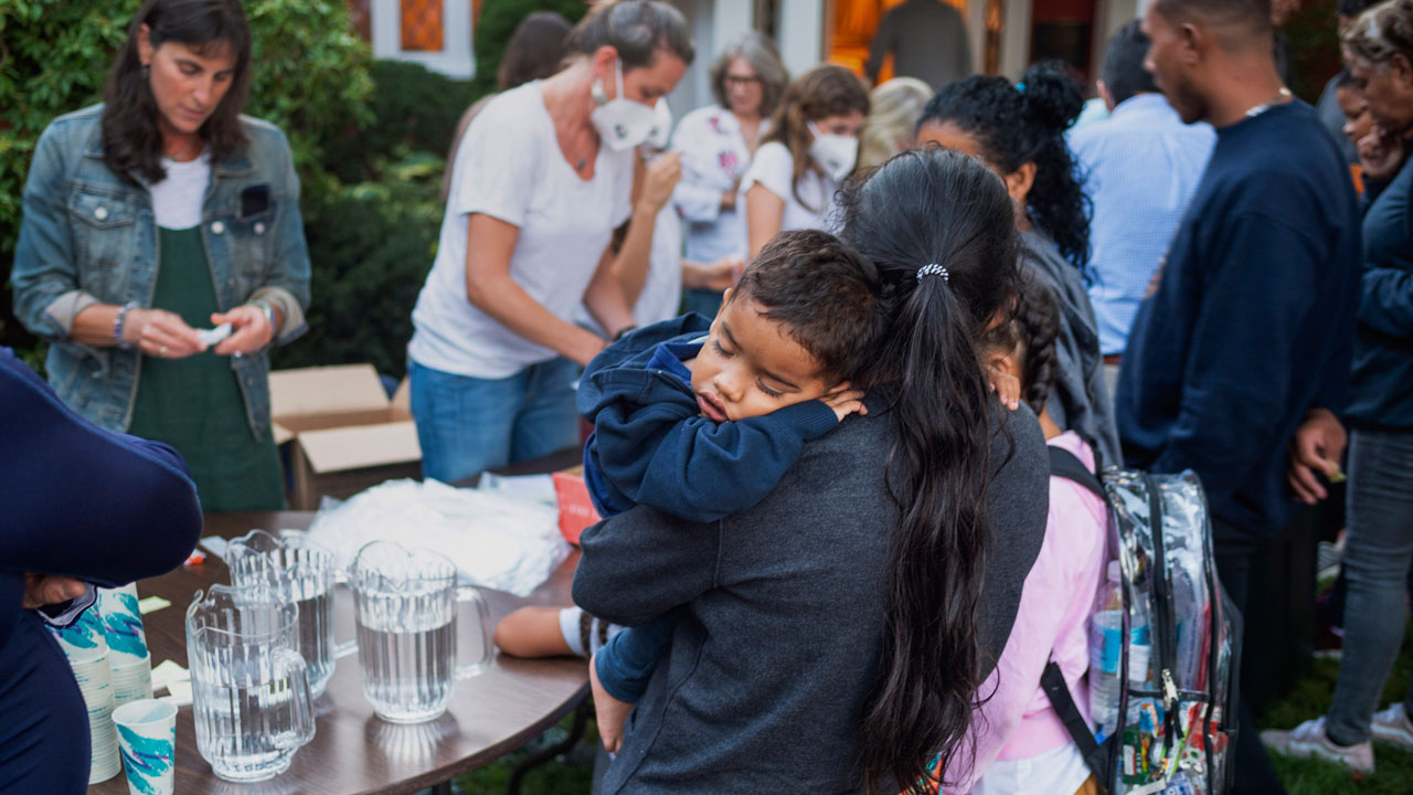A woman, who is part of a group of immigrants that had just arrived, holds a child as they are fed outside St. Andrews Episcopal Church, Wednesday Sept. 14, 2022, in Edgartown, Mass., on Martha's Vineyard. Florida Gov. Ron DeSantis on Wednesday flew two planes of immigrants to Martha's Vineyard, escalating a tactic by Republican governors to draw attention to what they consider to be the Biden administration's failed border policies.