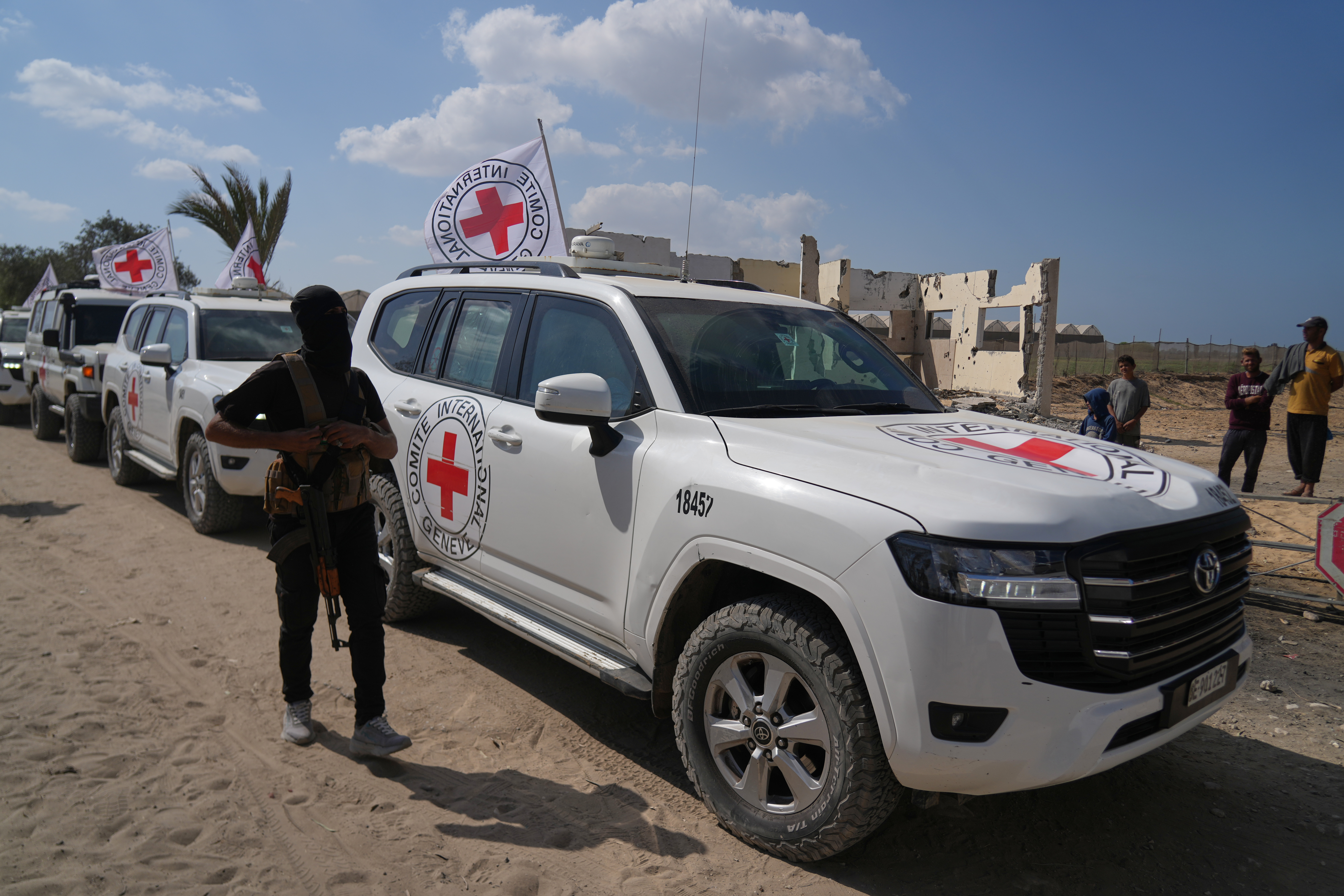 A masked Hamas gunman stands next to Red Cross vehicles arriving for the handover of Israeli hostages by Hamas, in Khan Younis, southern Gaza Strip, Monday, Oct. 13, 2025. 