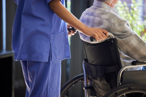 Stock image of a healthcare professional assisting an elderly person in a wheelchair.