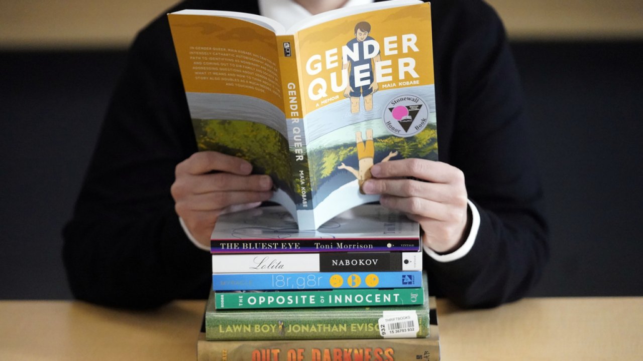A person poses with books that have received complaints.