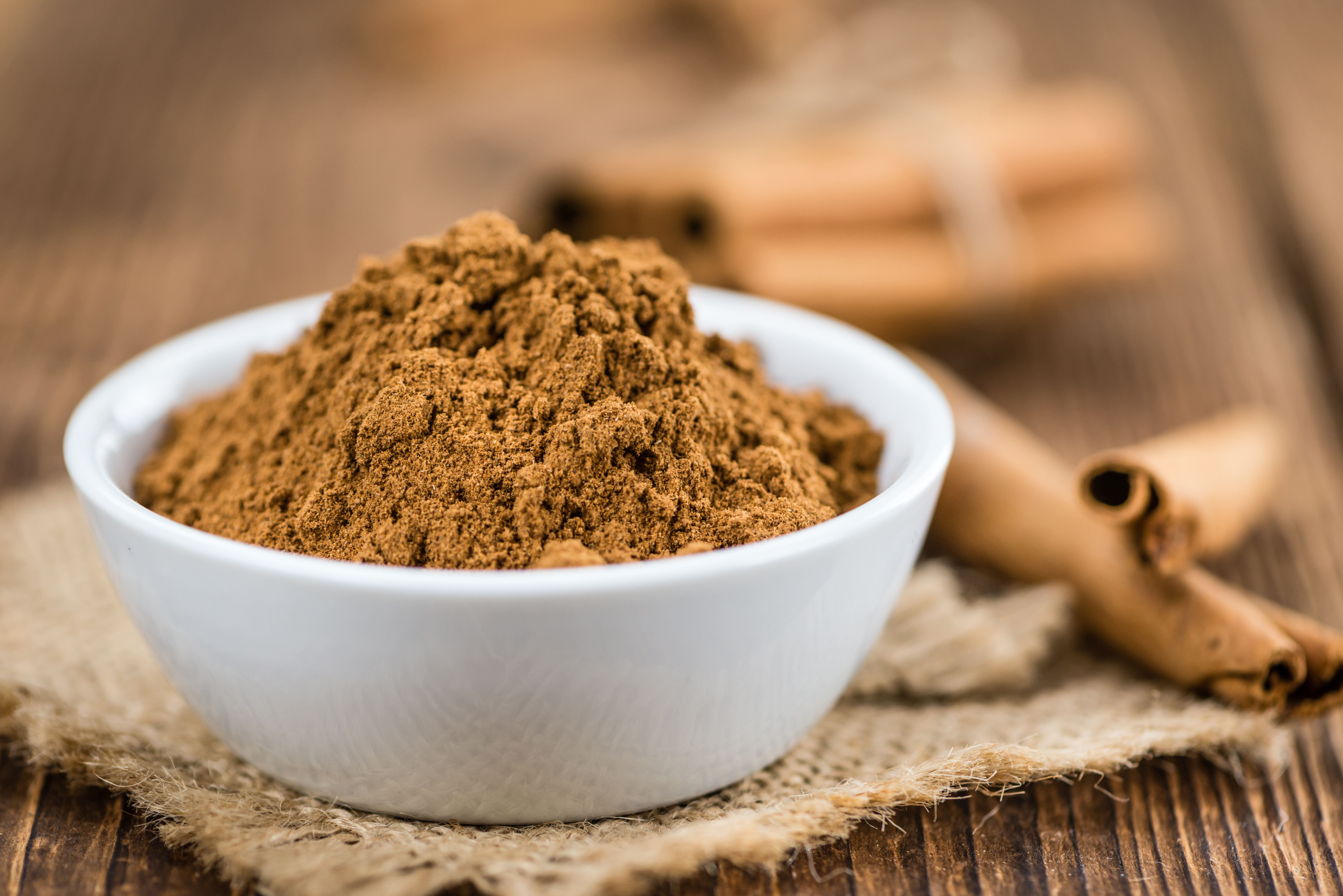 Ground cinnamon in a bowl on a table. 