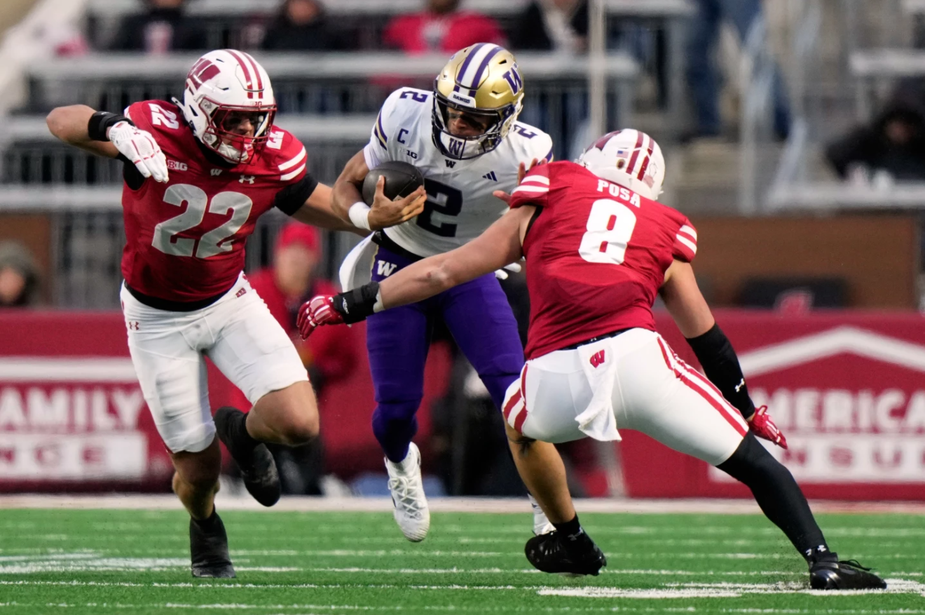 Washington's Desmond Williams Jr. tries to run between Wisconsin's Mason Reiger and Mason Posa during the first half of an NCAA college football game Saturday, Nov. 8, 2025, in Madison. 