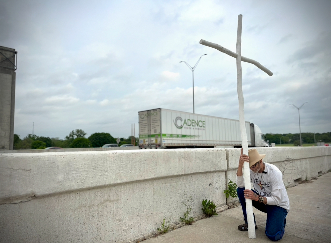 Pastor Ronnie Woods praying next to I-35 as he meets the halfway point in his walk.