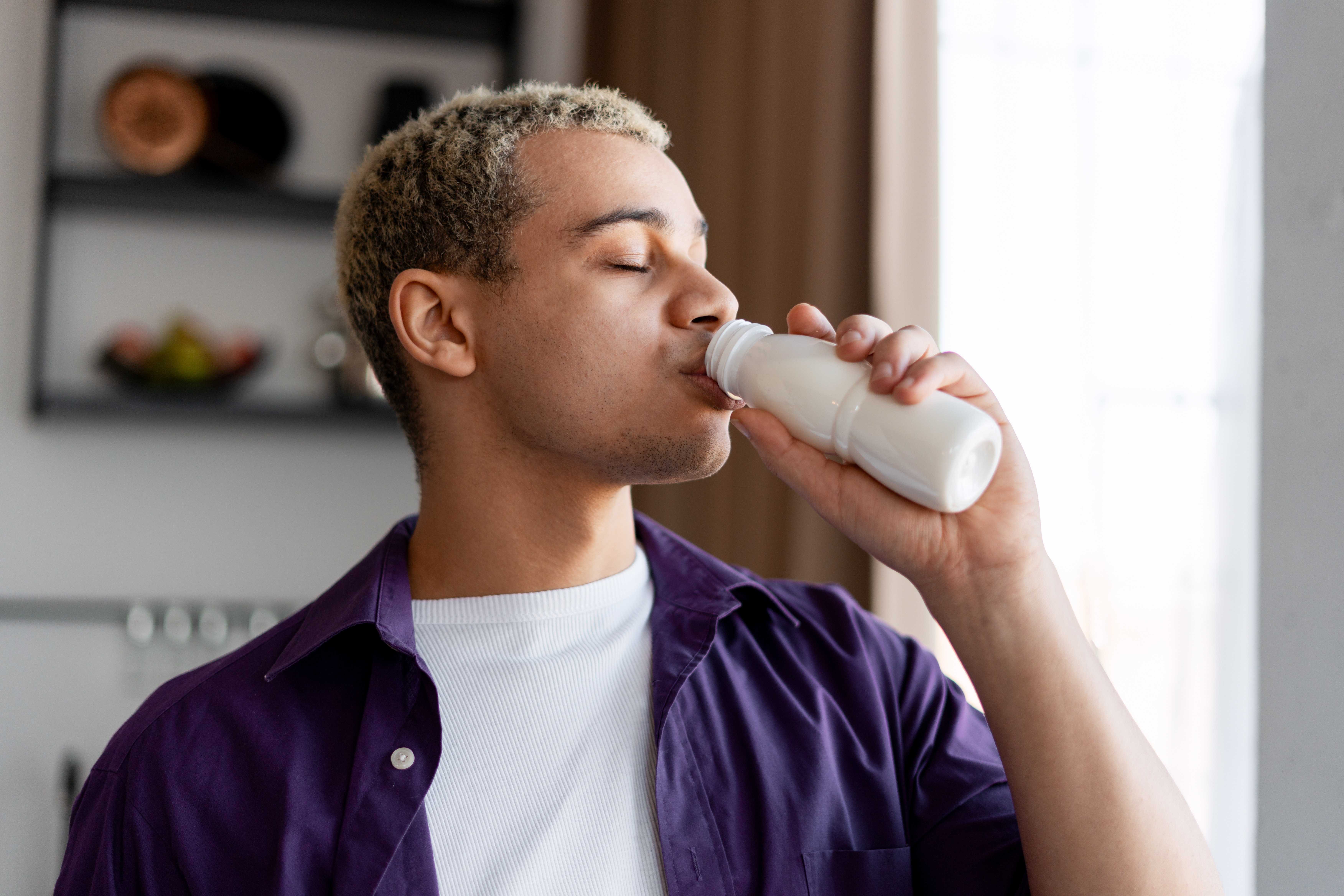 Man drinking a probiotic beverage from a bottle.