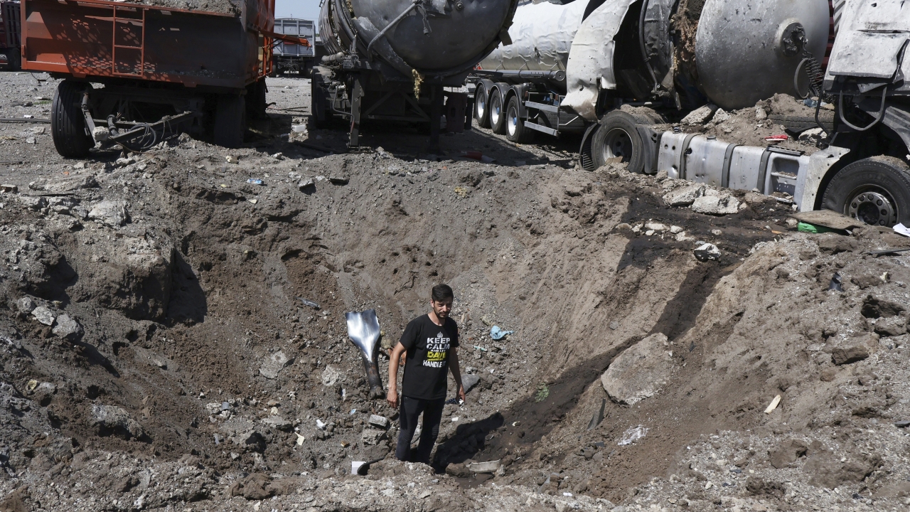 A man stands inside a crater after Russian shelling in Ukraine.