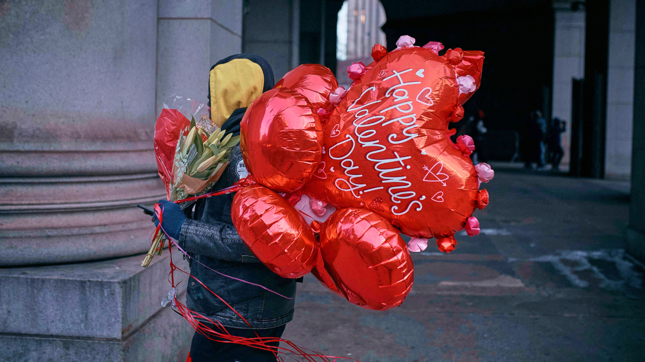 FILE - A man walks holding flowers and balloons on Valentine's Day, Friday, Feb. 14, 2025, in New York.
