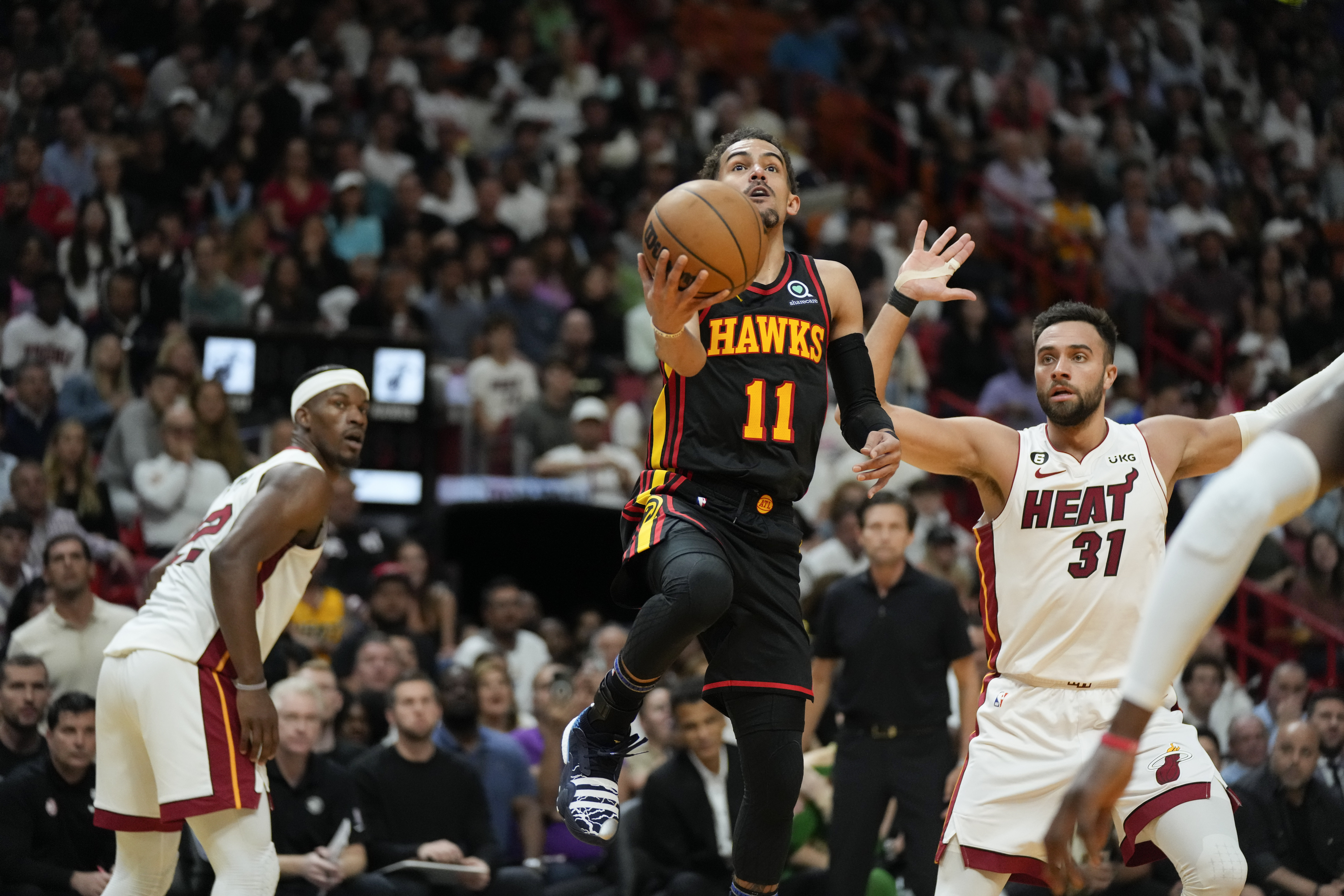 Atlanta Hawks guard Trae Young looks for opening past Miami Heat guard Max Strus and forward Jimmy Butler in NBA play-in game, April 11, 2023
