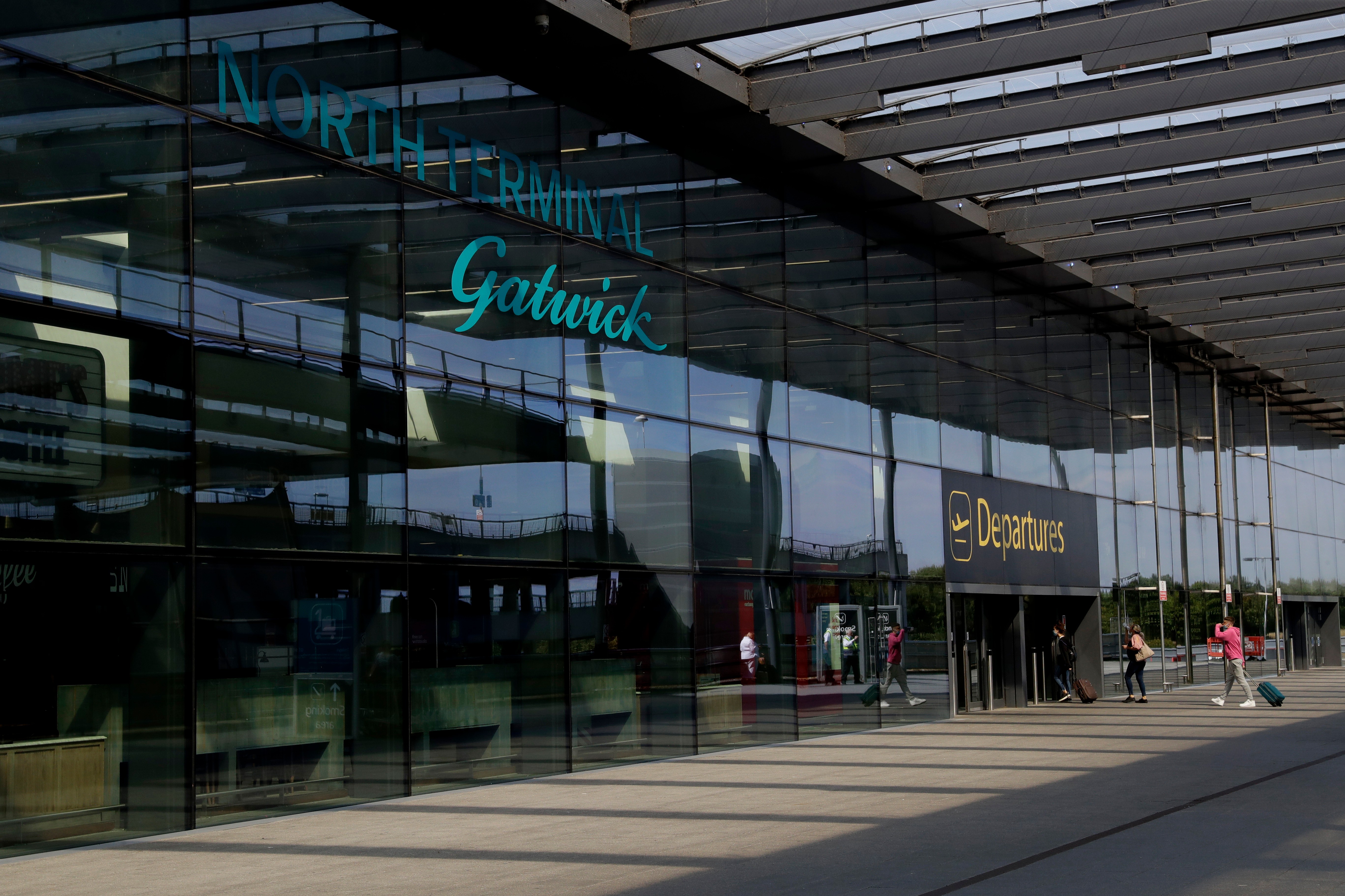 FILE - Passengers walk into the Departures entrance at the North Terminal of Gatwick Airport.