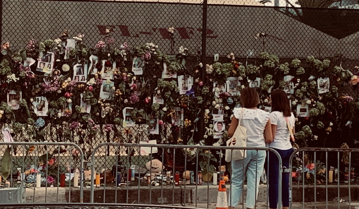 Women stare at makeshift memorial for Surfside condo collapse victims, June 29, 2021