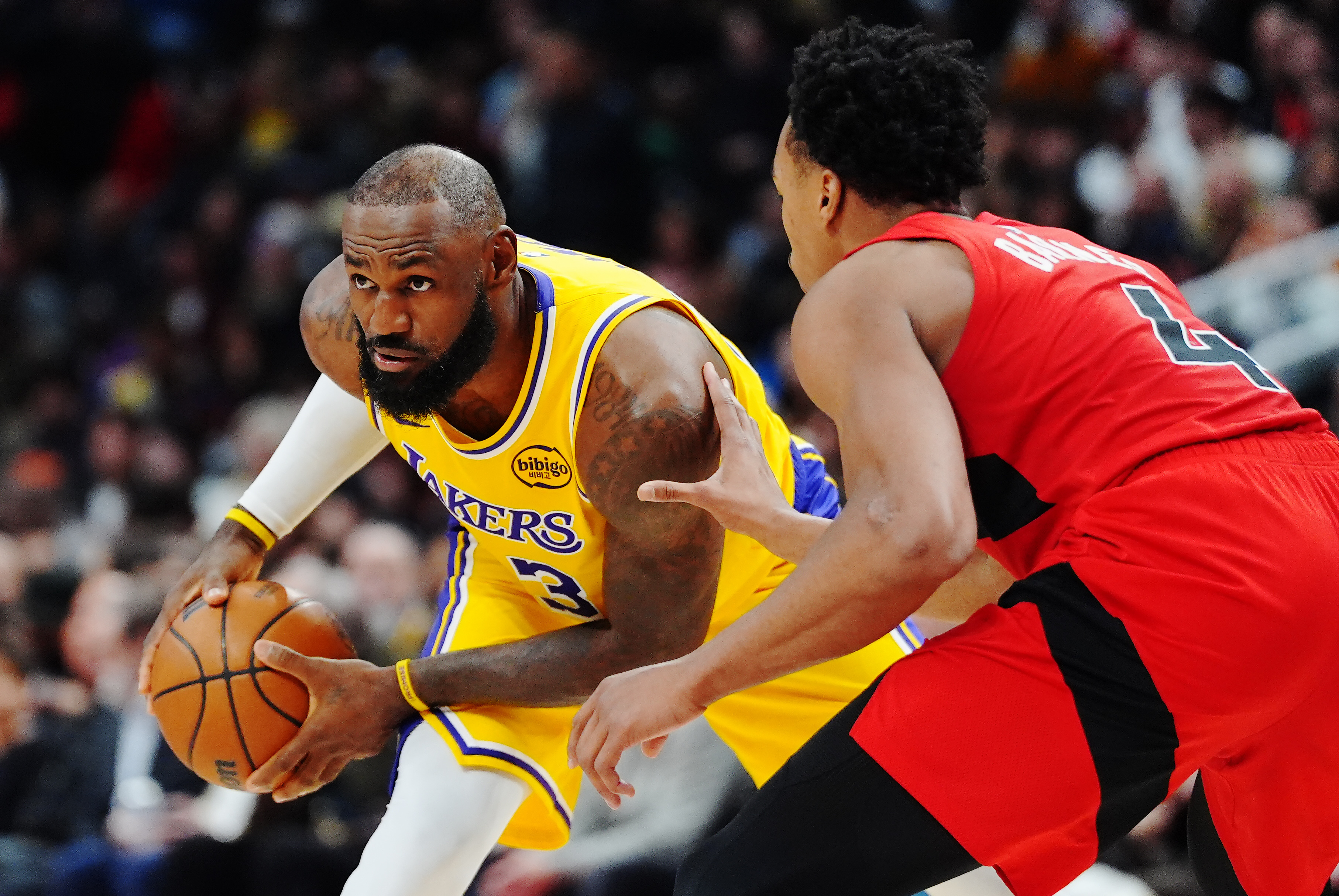 Los Angeles Lakers' LeBron James, left, is guarded by Toronto Raptors' Scottie Barnes (4) during second-half NBA basketball game action in Toronto, Thursday, Dec. 4, 2025. 