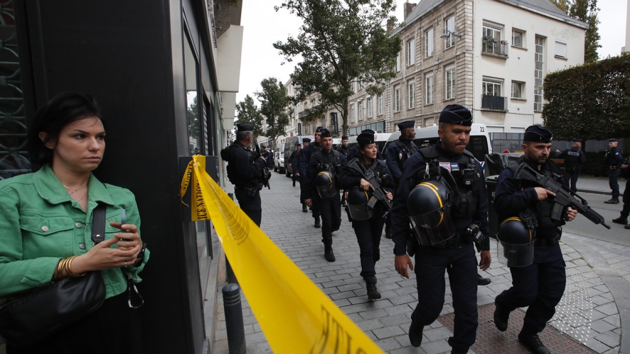 Riot police officers patrol the area after a man armed with a knife killed a teacher and wounded two others in France.