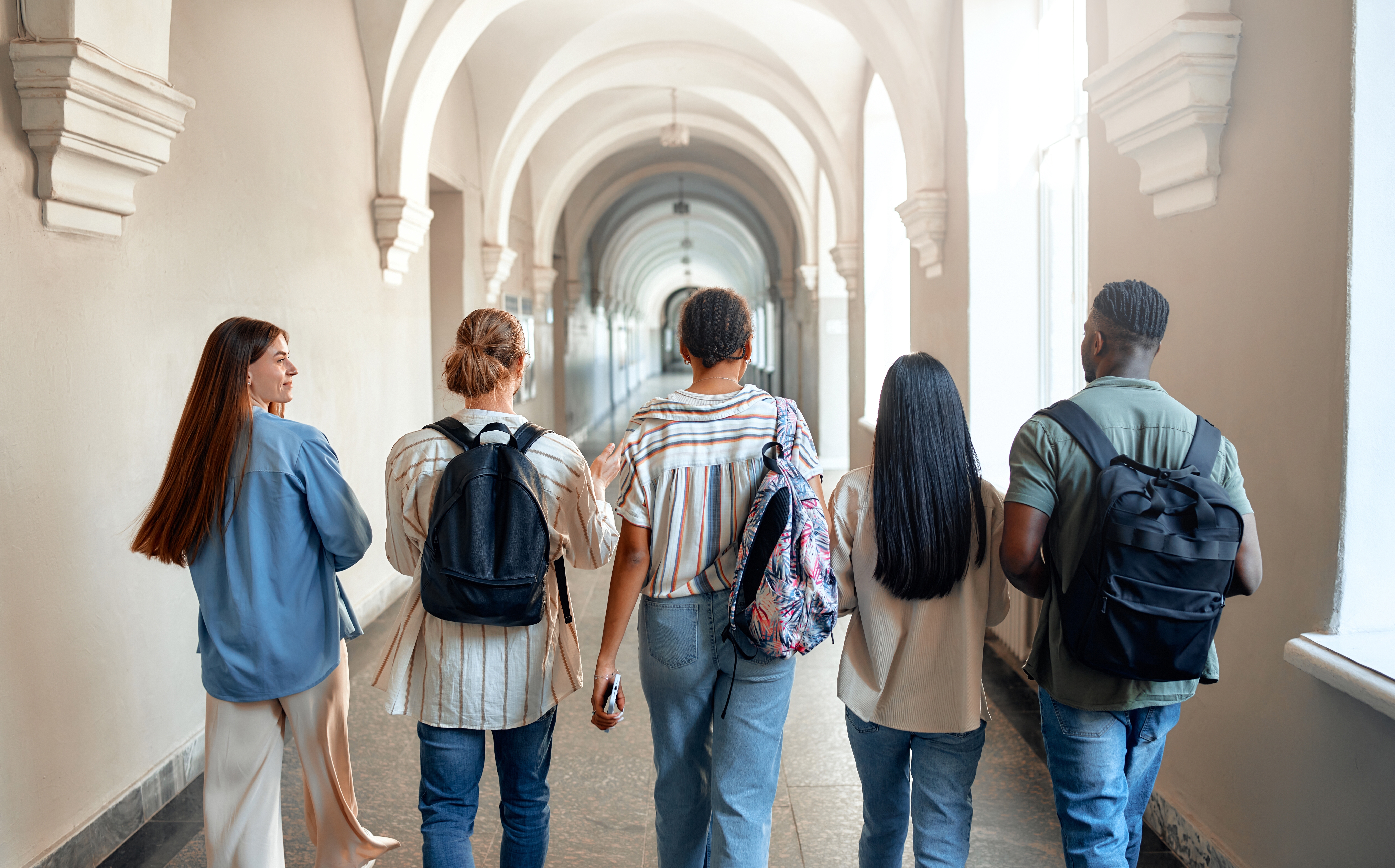 A group of college students walks down a hallway.