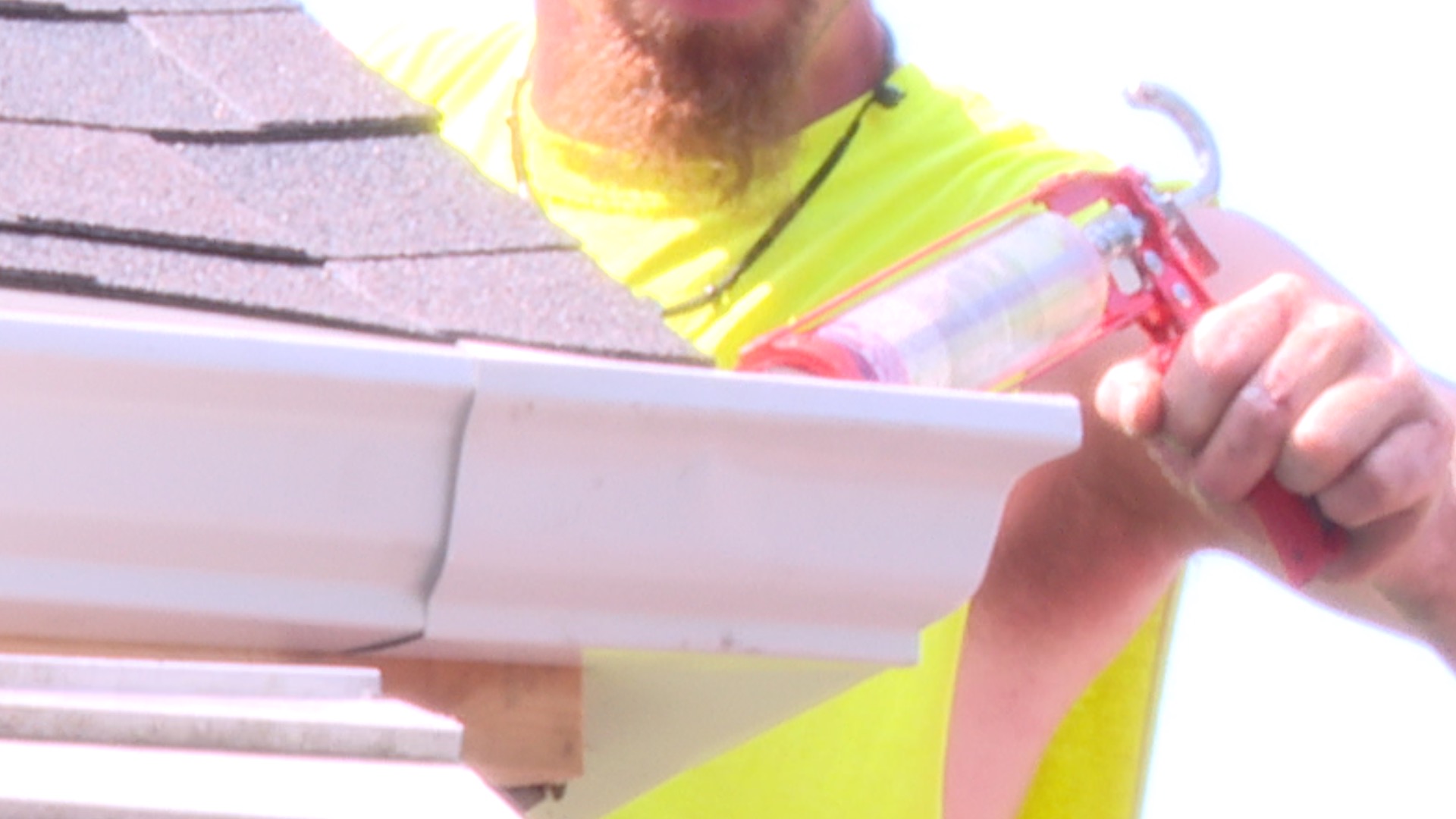 CS Roofing worker drills gutter on a roof on a hot day