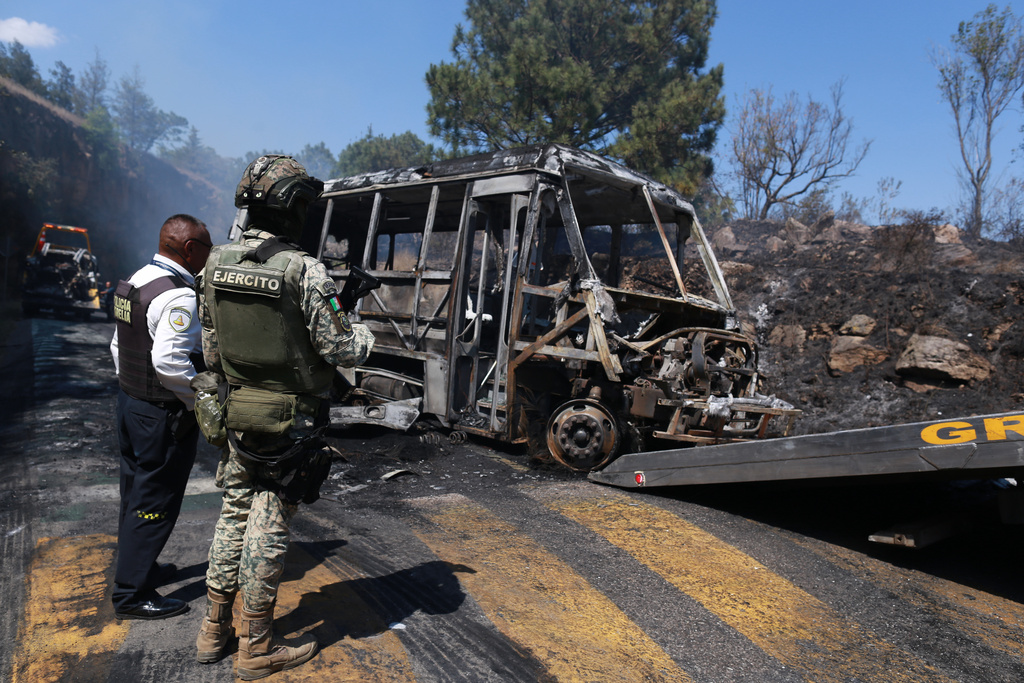 A soldier stands guard by a charred vehicle that was set on fire in Cointzio, Mexico, Sunday, Feb. 22, 2026, amid reports the Mexican Army killed Jalisco New Generation Cartel leader Nemesio Oseguera, known as "El Mencho."