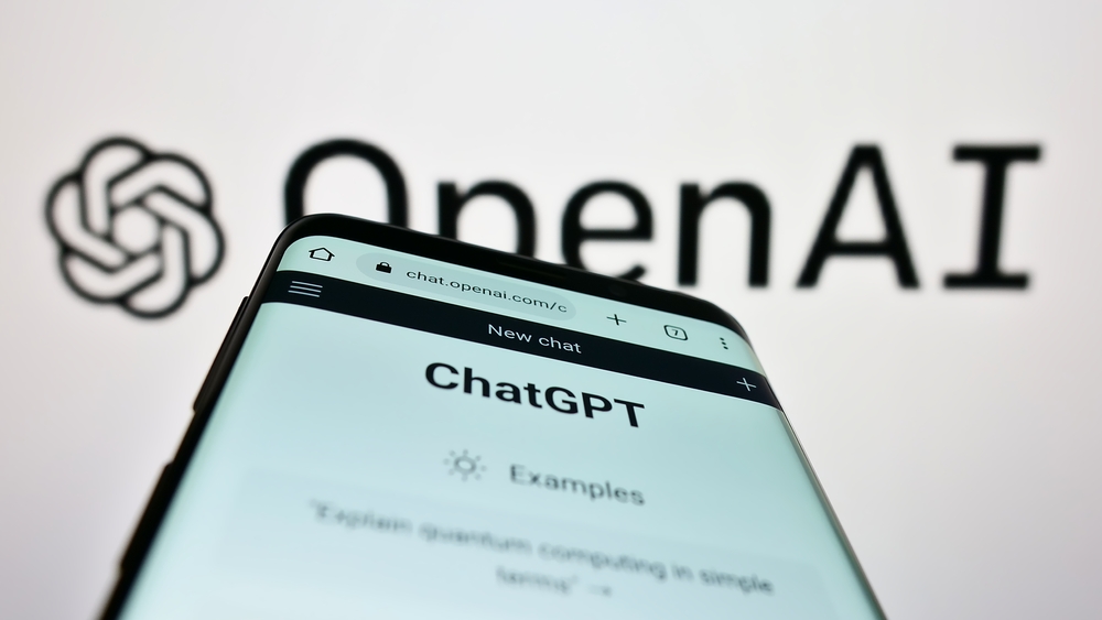 Mobile phone with website of US artificial intelligence company OpenAI LLC on screen in front of business logo.